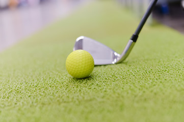 Golf club and ball on green indoor grass background
