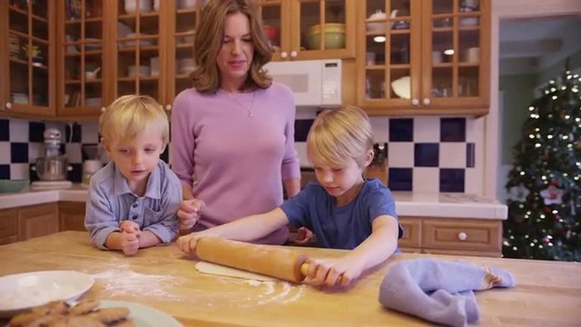 Cute young caucasian child blending cookie dough with mom and brother