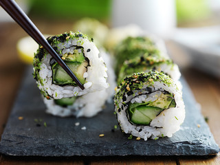 healthy kale and avocado sushi roll with chopsticks