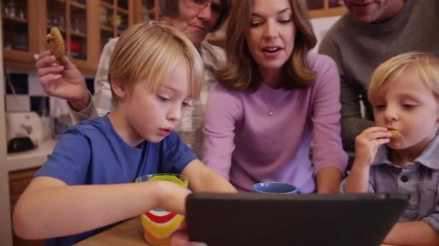 Closeup of a beautiful caucasian famly enjoying cookies while watching an ebook