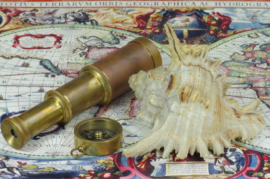 Vintage telescope, compass and shell lie on the old map of the world.