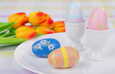 Colored Easter Eggs and Egg Cups With Tulips in Background