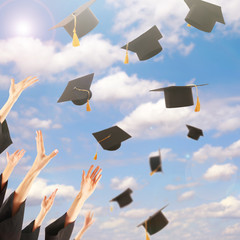 Graduates hands throwing graduation hats in the sky