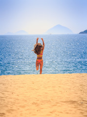 blonde slim girl in bikini runs from sea on sand laughs