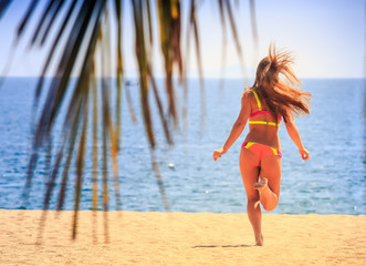 Naklejka premium blonde slim gymnast in bikini backside view runs to sea