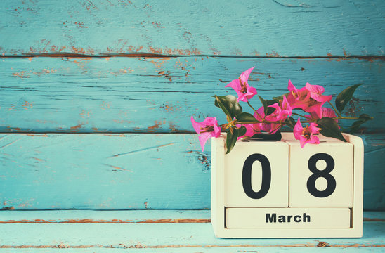 wooden March 8 calendar, next to purple flowers on old blue rustic table. selective focus. vintage filtered