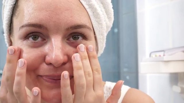 Woman in towel on head with no makeup making face massage 4K