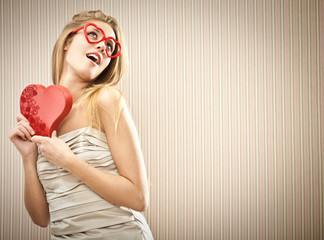 Beautiful blonde girl with heart glasses with chocolate box love gift