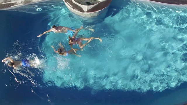 Upper view of family swimming in private swimming-pool