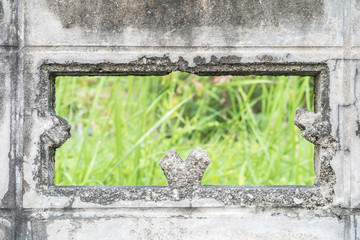 Closeup damaged dirty cement wall with blurred green grass background