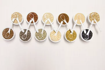 Fotobehang Ancient grains in white ceramic bowls with spoons, a healthy gluten free alternative © Kelly