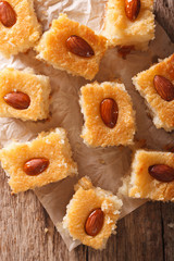 cake with almonds basbousa close-up on paper. vertical top view
