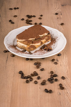 Still life with tiramisu cake in a white plate and a coffee beans decoration