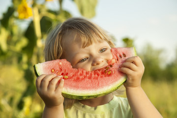 happy child eating watermelon in the garden