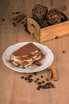 Still life with tiramisu cake in a white plate and a coffee beans decoration