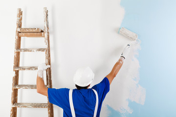 painter painting a wall with paint roller - 101692424