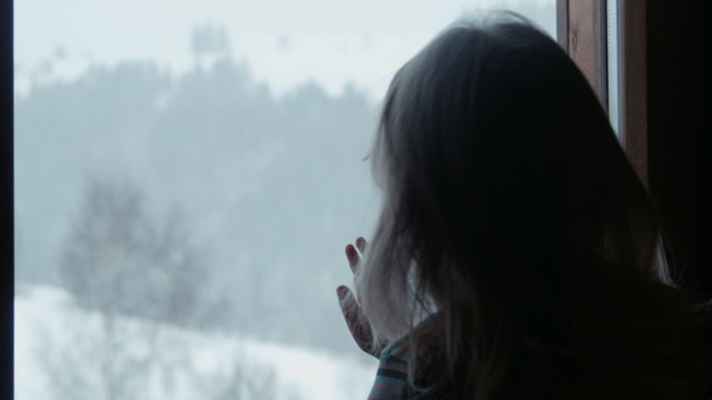Little cute girl behind window in winter