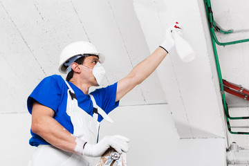 worker spraying ceiling with spray bottle