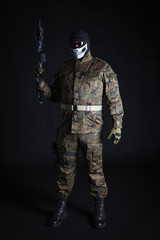 Anti terrorist dressed in camouflage, standing with a gun, looking at camera