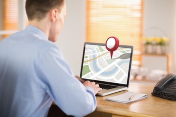 Composite image of businessman working on his laptop