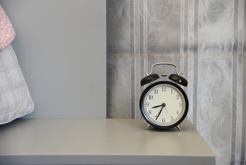 classical alarm clock on bedside table