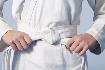 Photo sur Plexiglas Arts martiaux Mains serrant la ceinture blanche sur un adolescent vêtu d& 39 un kimono