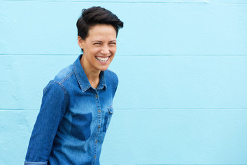 Young woman laughing against blue background - Powered by Adobe