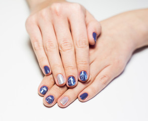 Fototapeta premium Close up of female hands with professional blue and silver manicure isolated on white background. Art stamping on nails. Modern gel polish with base coat first and top cure with UV or LED lamp.