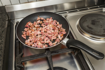 Fried bacon pieces in the non-sticking pan.

