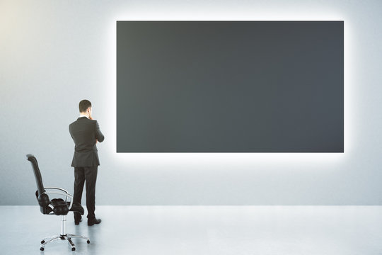 Blank black big poster on the wall and businessman with leather