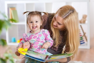 Happy young woman and child girl watching a baby booklet