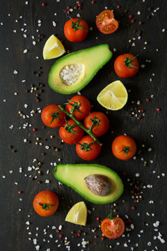 Fresh vegetables. Avocado, tomatoes, lime, peppers and sea salt on dark wooden background