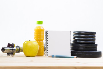 Sport Equipment. Free Weights, Barbell, Apple, Orange Juice  And Notepad To Workout Plan On Wooden Table. Sport Fitness Background