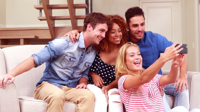 Smiling friends taking selfies with smartphone