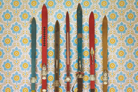 Vintage colorful used skis in front of retro wallpaper