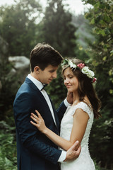 beautiful happy bride with flower wreath and stylish groom under