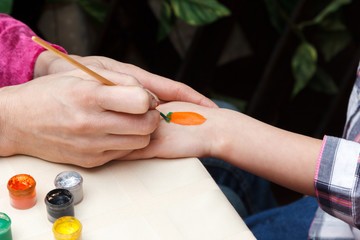 woman draws carrot on girl hand