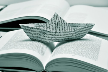paper boat on an open book, black and white