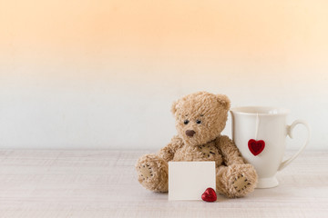 Valentine's day concept with Teddy bear, blank card  and mug on wooden table