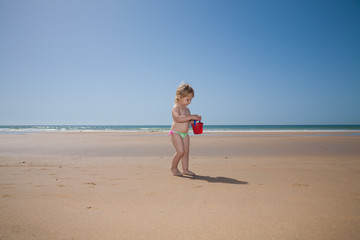 Fototapeta na wymiar baby with red bucket at beach