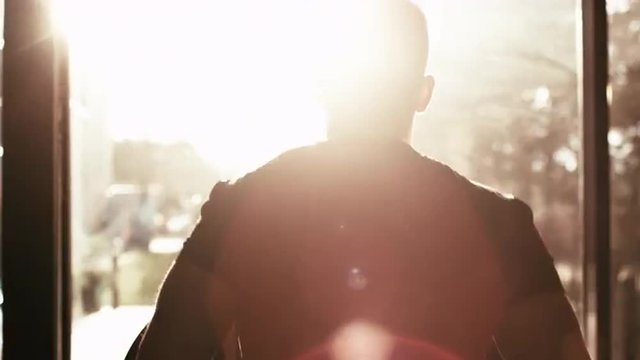 Close-up footage of male silhouette against sun running on treadmill in sport gym. Shot on RED Cinema Camera.