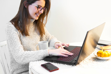 Naklejka premium Young woman sitting at the table, using a laptop