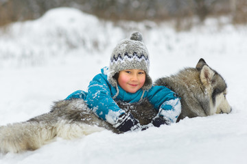 happy boy playing with dog or husky outdoors in winter day