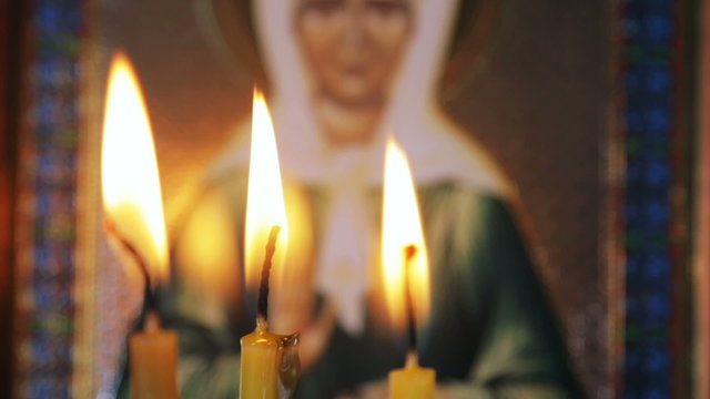 burning candles in front of the holy icons, soft focus
