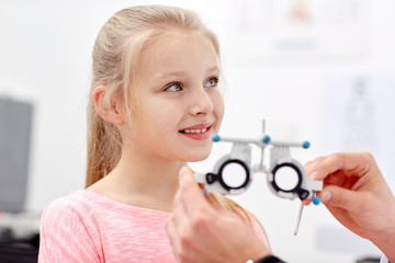 optician with trial frame and girl at clinic
