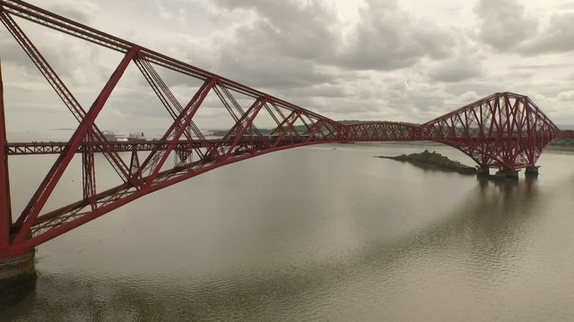 Stunning aerial shot of the Forth Rail Bridge during the day in South Queensferry with a local train passing

