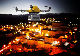  modern transport drone carries a parcel flying at night over an illuminated city. fast and modern delivery concept. - obrazy, fototapety, plakaty