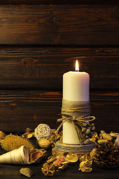 Big white candle on rustic wooden background.