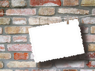 Close-up of one hanged postcard with peg on brick wall background