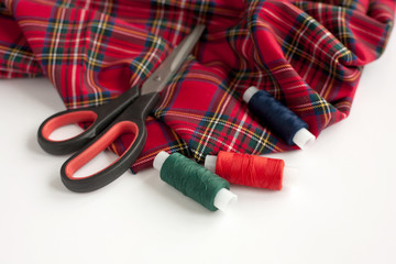 The tartan fabric, scissors and sewing threads